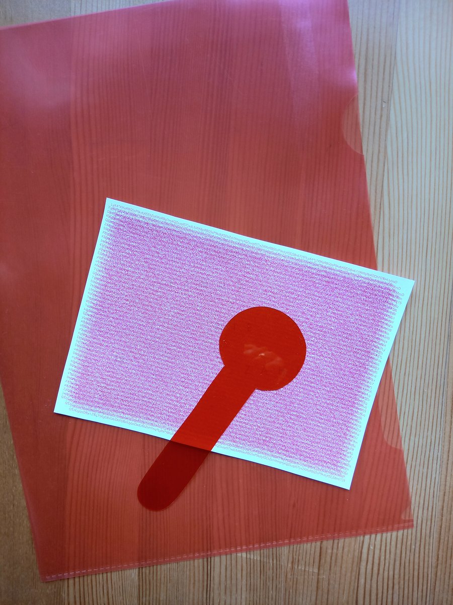 Karte mit rotem Störmuster auf rotem Sichtmäppchen mit transparenter roter Plastik-"Lupe"