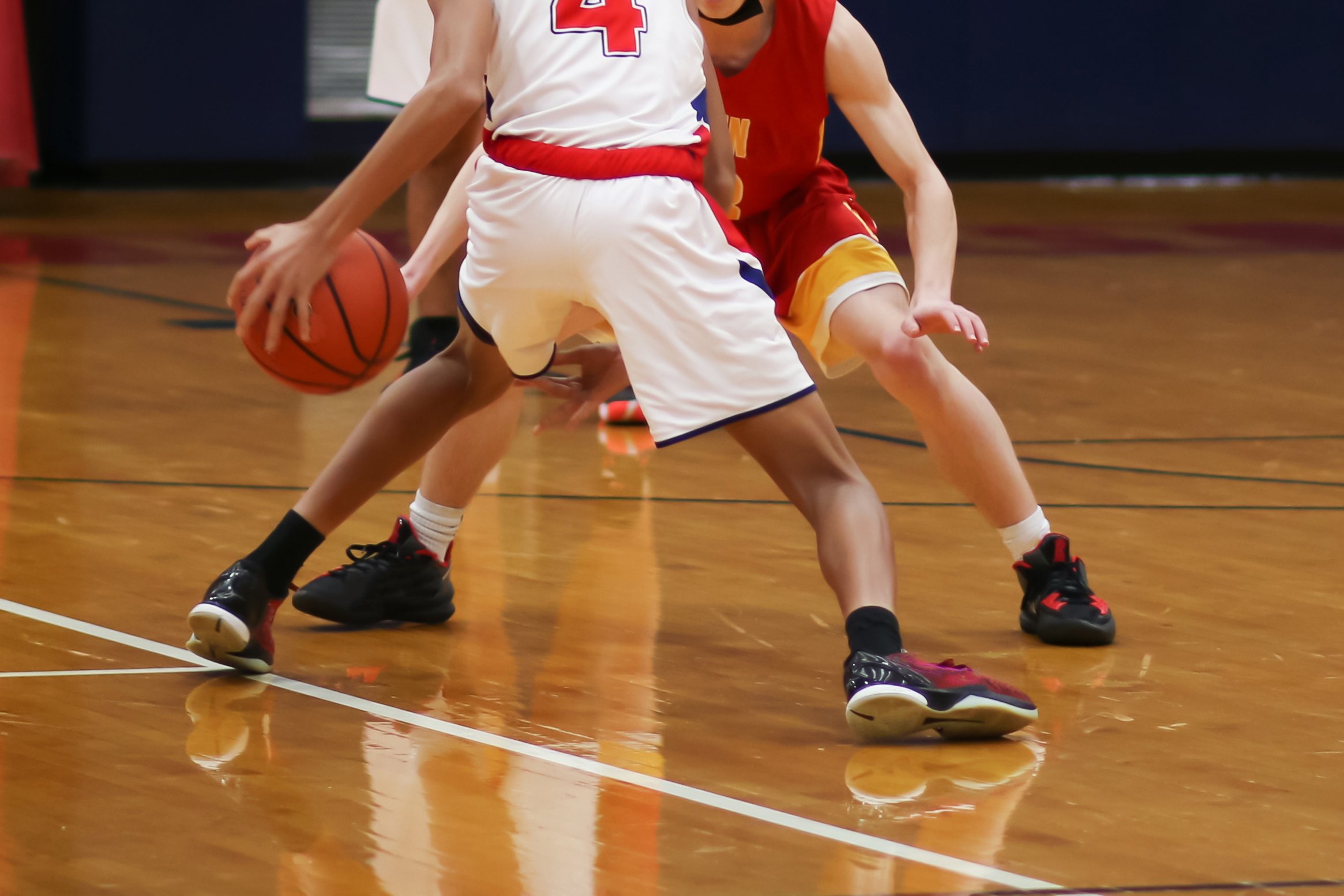 Junge Basketballspieler in der Turnhalle, Fokus auf Beine und Ballhand