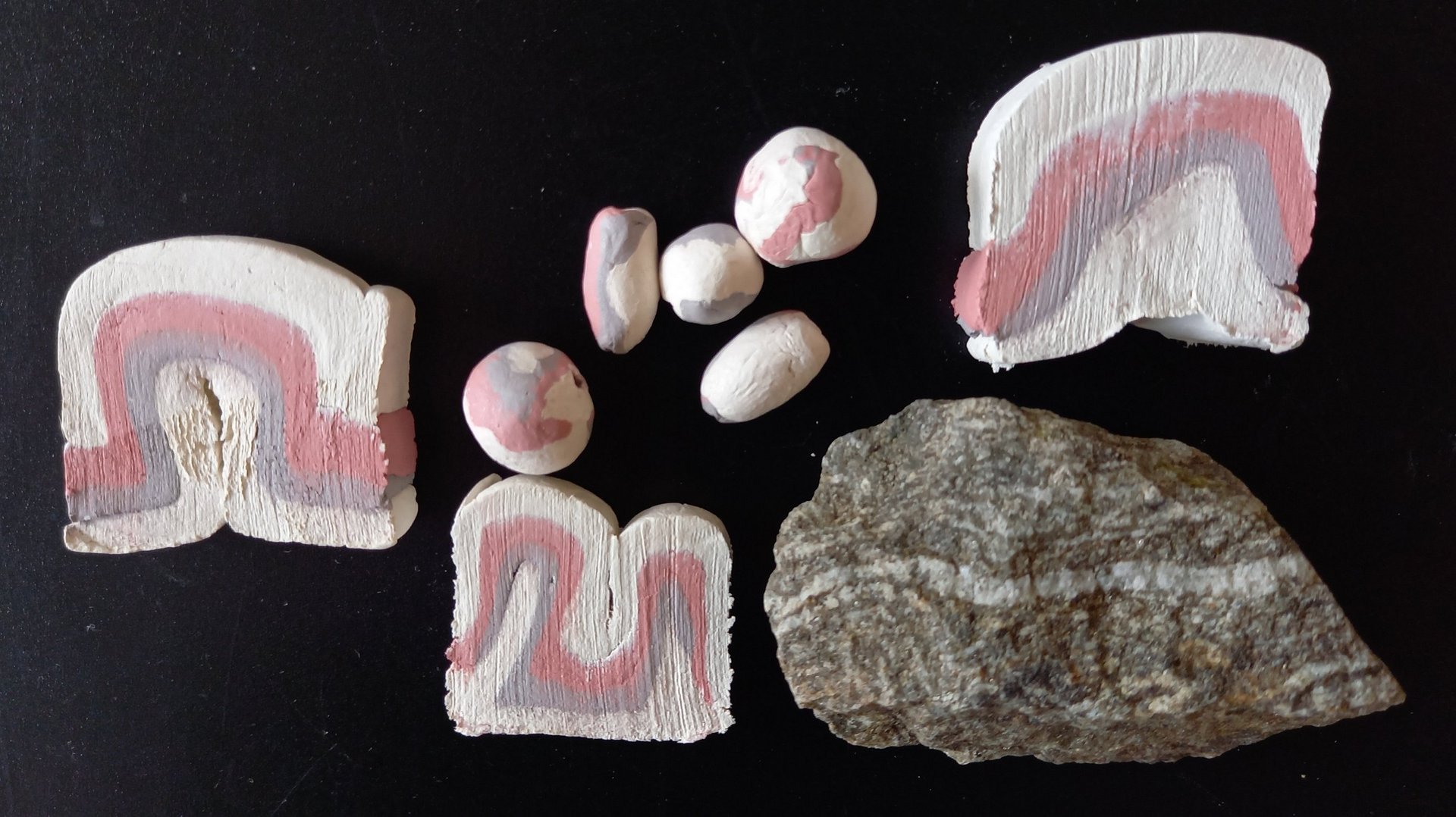Ein Stein und mehrere Scheiben und Kugeln aus geschichteter, verschiedenfarbiger Modelliermasse